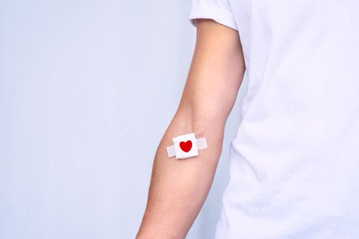 Blood donation concept with copy space. Blood donor with bandage after giving blood on a white background. High quality photo