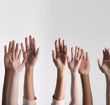 Shot of a diverse group of unidentifiable people holding their hands up against a white background