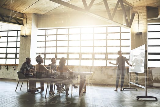 Multiple exposure shot of businesspeople having a meeting superimposed over a cityscape