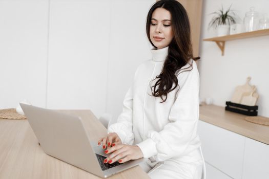young woman working in laptop at home indoor in white colours. High quality photo