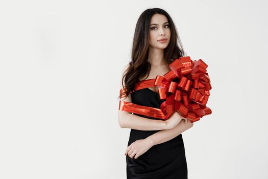 Young pretty woman wrapped with ribbon, red gift ribbon. High quality photo