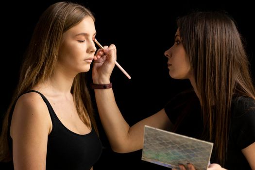 Young beautiful woman applying make-up by make-up artist. Make up in process
