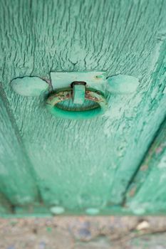 Closeup of vintage run-down wooden door, green painted, selective focus