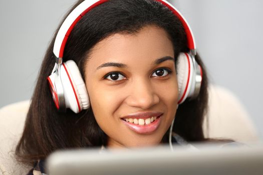 Portrait of a beautiful woman in white headphones. African teen girl, face close-up. Online training