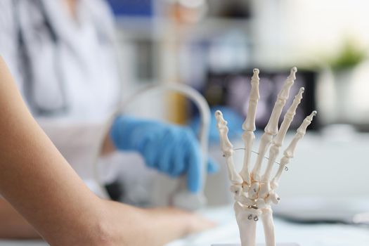 On the doctor's table is a plastic skeleton of the fingers, close-up. Ultrasound of the wrist in the clinic