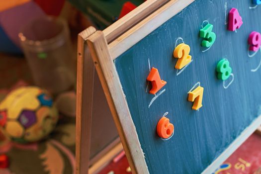 Learning numbers on a blackboard with colorful magnets and handwriting on blackboard during homeschooling. Quarantine lifestyle concept.