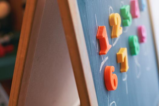 Learning numbers on a blackboard with colorful magnets and handwriting on blackboard during homeschooling. Quarantine lifestyle concept.