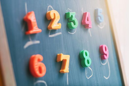 Learning numbers on a blackboard with colorful magnets and handwriting on blackboard during homeschooling. Quarantine lifestyle concept.