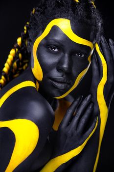 Yellow and black body paint. Woman with face art. Young girl with bodypaint. An amazing model with makeup