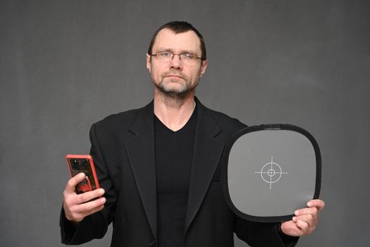 Caucasian adult man in glasses and jacket with phone looks at camera