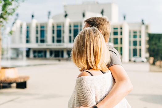 An adult mature happy romantic couple in love outdoors in city street park. A blonde caucasian man and woman spend time together. Senior wife and husband walking outside on square