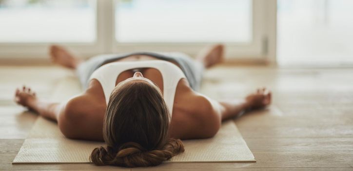 Shot of a young woman lying on her yoga mat after a workout