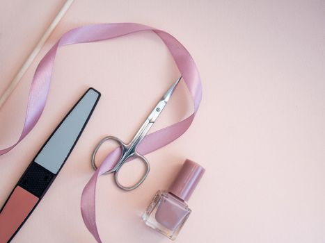 A set of cosmetic tools for manicure and pedicure on a pink background. Gel polishes, nail files, manicure scissors. photo