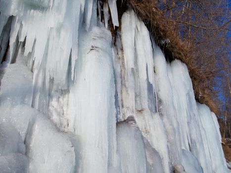 CLOSE UP Stunning frozen waterfall icicles on rocky mountain cliff on winter day.