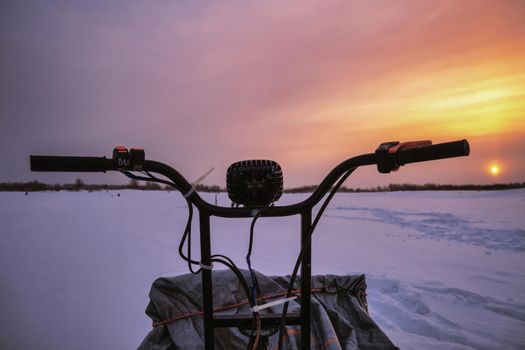 snowmobile steering wheel close-up at sunset background