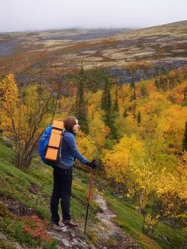 A young woman with a backpack and trekking poles in the Khibiny mountains. The concept of a healthy and active lifestyle. Girl on the background of nature mountains. photo