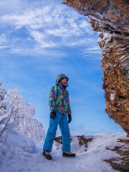 Woman hiker in winter near a cliff in the Urals. Stone town, Russia