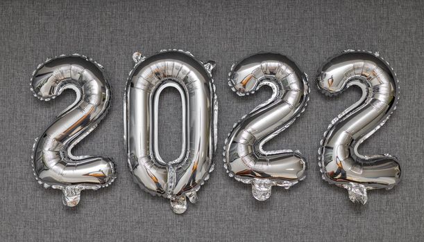 new year 2022 shiny silver balloons on grey background. High quality photo