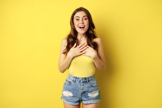 Portrait of enthusiastic, hopeful woman looking with yearning, smiling happy face, expecting smth, desire, standing over yellow background.