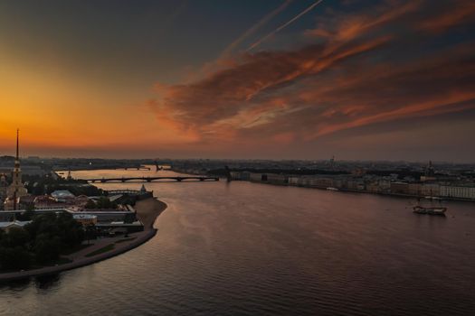 The Peter and Paul Fortress at sunrise, reflection of the orange and pink sky on the water, drawbridges Troitsky and Liteiny are separated. High quality photo