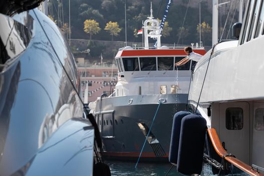 A lot of huge yachts are in port of Monaco at sunny day, Monte Carlo, mountain is on background, glossy board of the motor boat, megayachts are moored in marina, sun reflection on glossy board. High quality photo