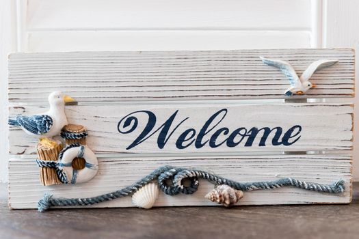 Welcome sign on antique rustic wooden sign with sea birds, Anchor and lifebuoy decoration.