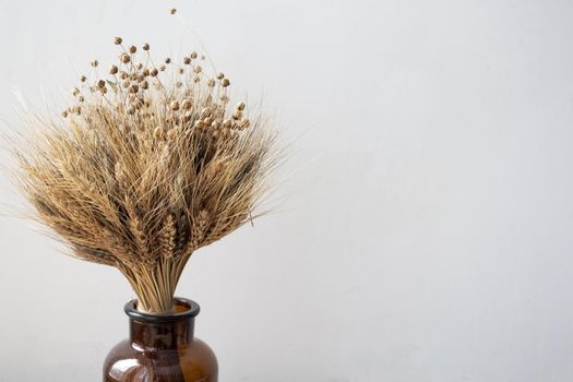 A simple brown vase with a bouquet of wheat. Minimalistic concept. Place for your text. White background. Home decor. Minimalism and simplicity.