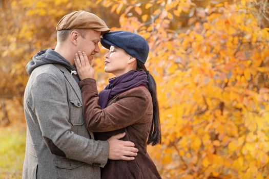 Caucasian Fall Couple Looking at Each Other's Eyes. Casual Couple in Stylish Caps in an Autumn Suburb. Close-up. Fall Background. High quality photo