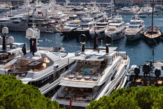A lot of huge yachts are in port Hercule of Monaco at sunny day, Monte Carlo, many small boats are on background, interiors of motor boat, chilling zone of megayachts, sun reflections on glossy boards. High quality photo