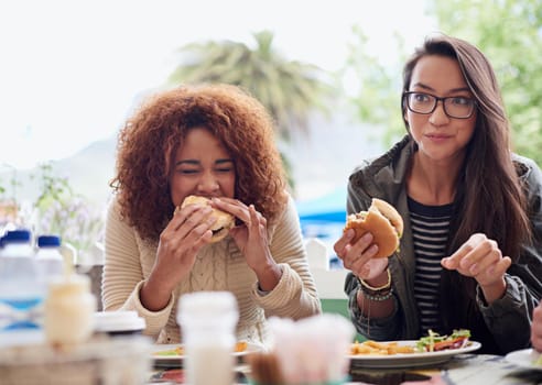Cropped shot of a friends eating burgers outdoors
