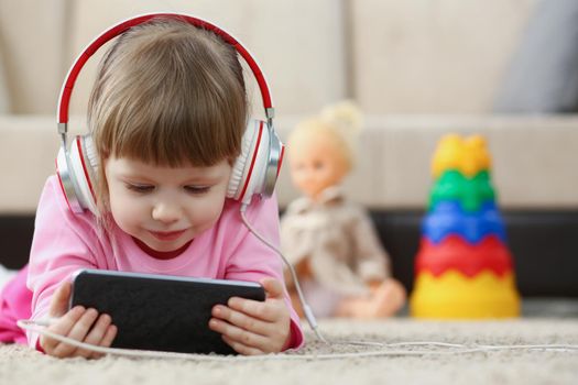 Low angle of little girl kid watching cartoon on smartphone device, digital entertainment for child. Funny pastime on holiday. Play, social media concept