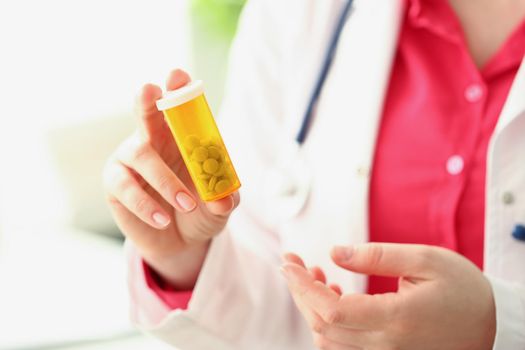 Close-up of doctor hold plastic container filled with tiny white pills, female intern advertises medication for recovery. Health, pharmacy, remedy concept