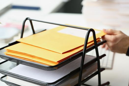 Close-up of businessman putting yellow envelope on holder for further delivery on address. Communication, inbox, post, correspondence, business concept