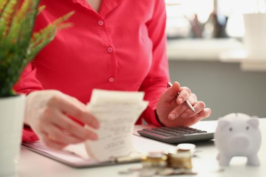 Close-up of female accountant count numbers on calculator, stacks of coins on office desk. Calculation of income, tax expenses. Business, finance concept