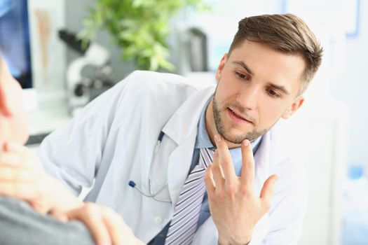 Portrait of young man medical worker in white uniform, give consultation to patient about neck pain. Young specialist in medicine. Healthcare, help concept