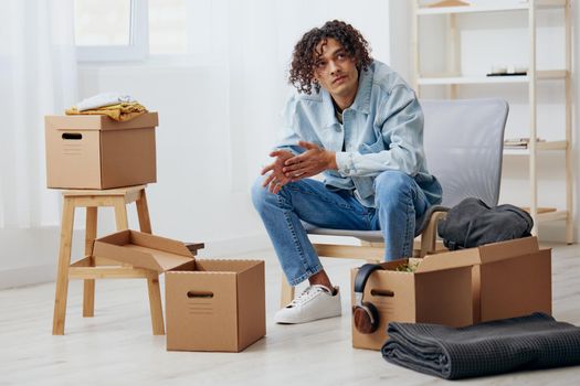 handsome guy sitting on a chair with boxes interior moving interior. High quality photo
