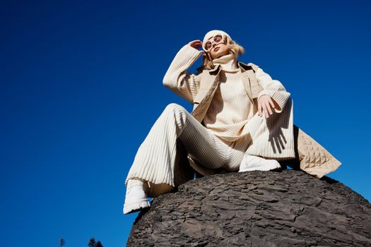 young woman in autumn clothes stands on a rock landscape blue sky lifestyle. High quality photo