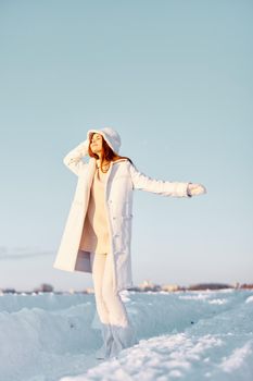 beautiful woman in a white coat in a hat winter landscape walk Fresh air. High quality photo