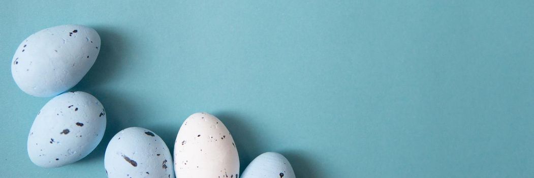 Easter background. Blue and white painted quail eggs on a blue background, decorated with cotton. Happy Easter holiday.