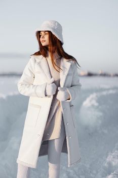 beautiful woman in a white coat in a hat winter landscape walk travel. High quality photo