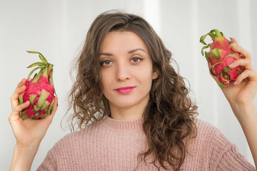 Young girl is holding two fresh ripe organic dragon fruits or pitaya, pitahaya. Exotic fruits, healthy eating concept.