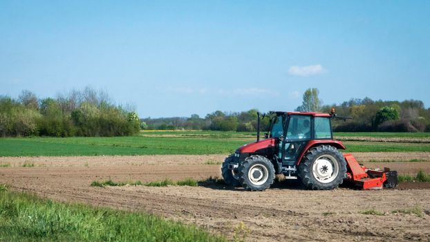 Red tractor ploughing the fields in early spring.