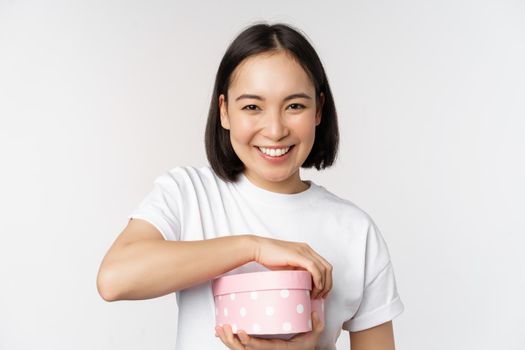 Happy asian woman, girlfriend open box with valentines day gift, receive romantic present, standing over white background. copy space