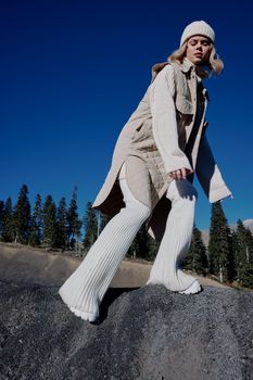 woman in autumn clothes stands on a rock landscape blue sky lifestyle. High quality photo