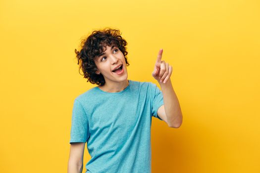 happy guy with curly hair shows thumb up yellow background. High quality photo