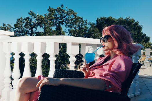 glamorous woman in sunglasses outdoors sitting on the terrace cocktail relaxing Lifestyle. High quality photo