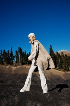 woman in autumn clothes stands on a rock landscape blue sky relaxation. High quality photo