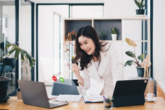 Asian business woman having video call with business team to consult about business plan of company. Online team meeting video conference