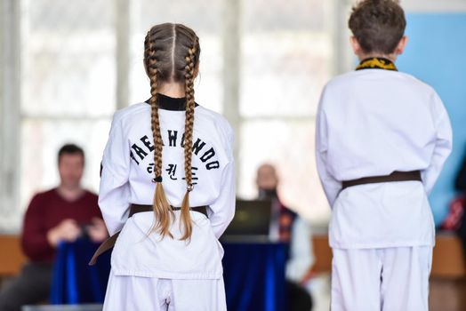 Taekwondo kids athlete stand on the court before doing the exercise. view from the back.