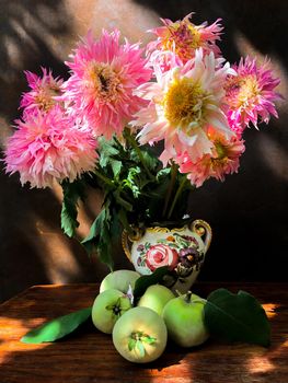 Romantic bouquet of dahlias and quince in a decorative ceramic vase in the rays of sunlight